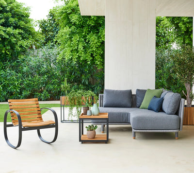 Corner outdoor couch shown on a white terrace with lush garden in the backgorund