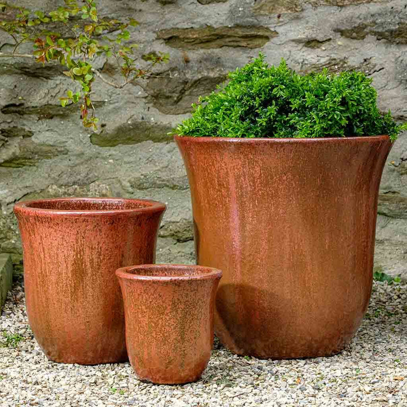 Grouping of 3 rust colored containers in front of stone wall