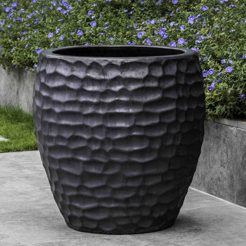 Black container shown in front of blue flowers