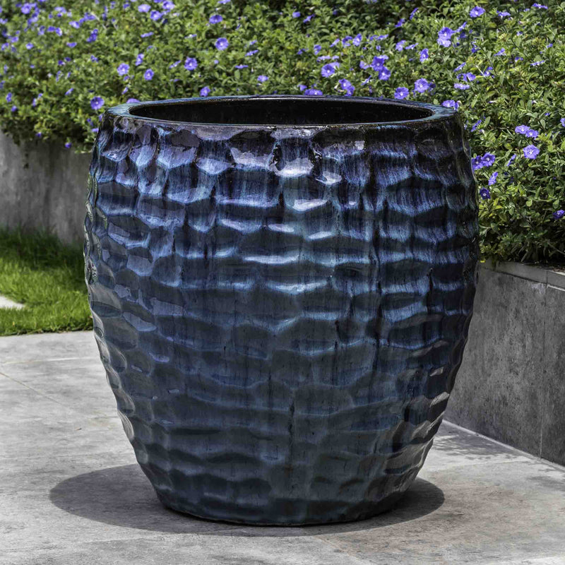 Dark grey container shown in front of blue flowers