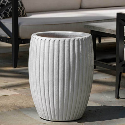 Tall white ribbed container in front of furniture
