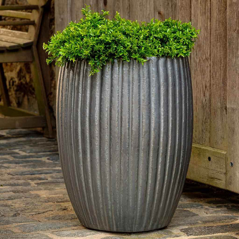 Tall grey ribbed container planted with a shrub