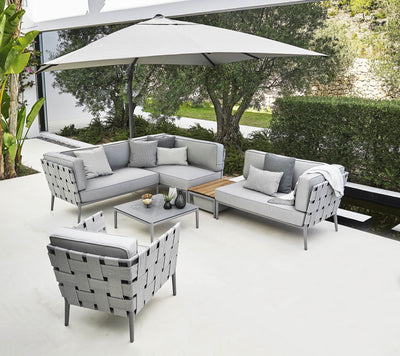 Outdoor deep sitting set in light gray with matching cushions under an umbrella