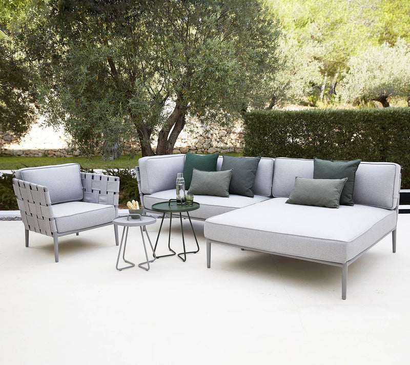 Outdoor deep sitting set in light gray with two coffee tables in front of large tree and green hedge