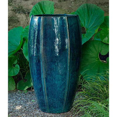 Tall dark blue container in front of large leaves