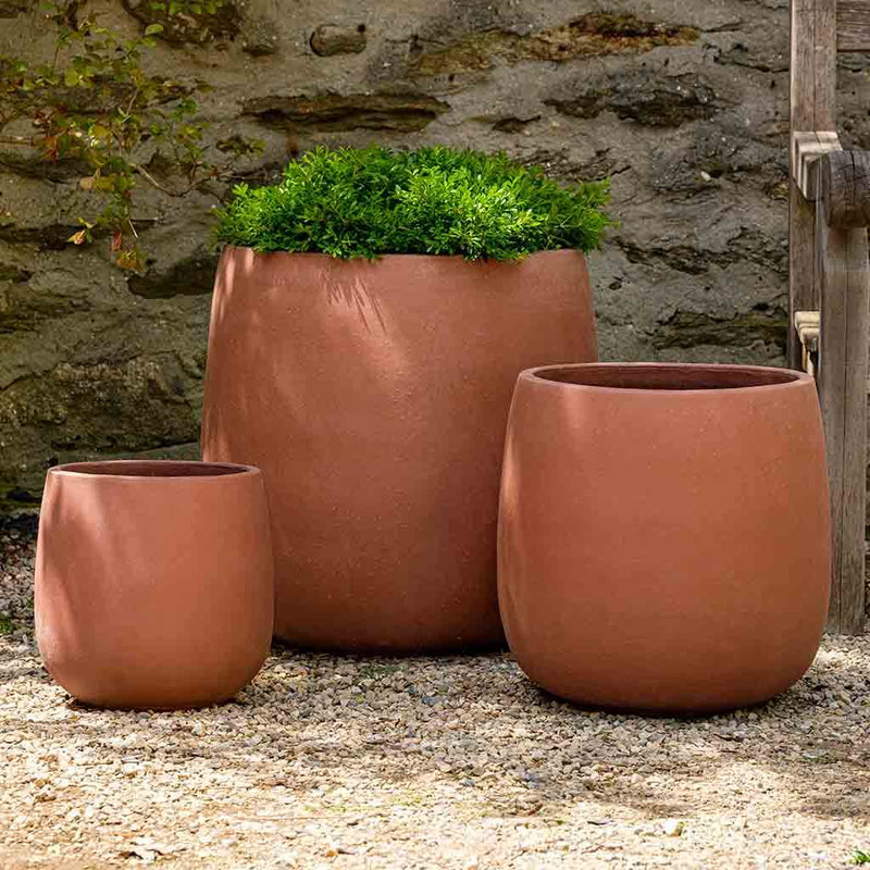 Grouping of 3 terra cotta containers shown in front of stone wall