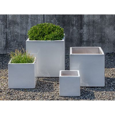 Grouping of 4 white containers shown in front of concrete wall