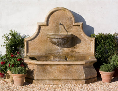 A traditional Spanish-style fountain pictured flanked by planted terra cotta containers.