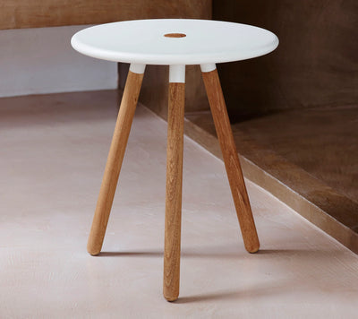 Stool with white top and wooden legs shown on white floor