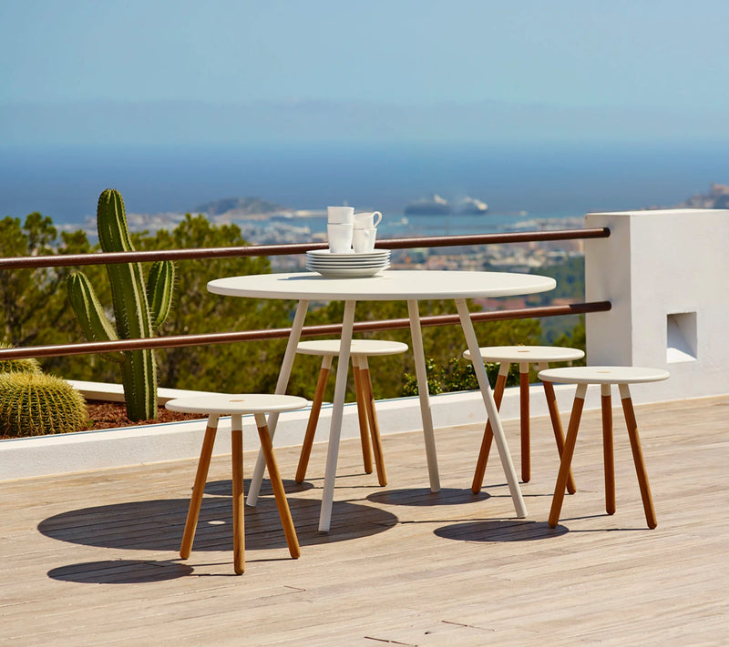 Round white table with four stools on rooftop terrace  with ocean in the background