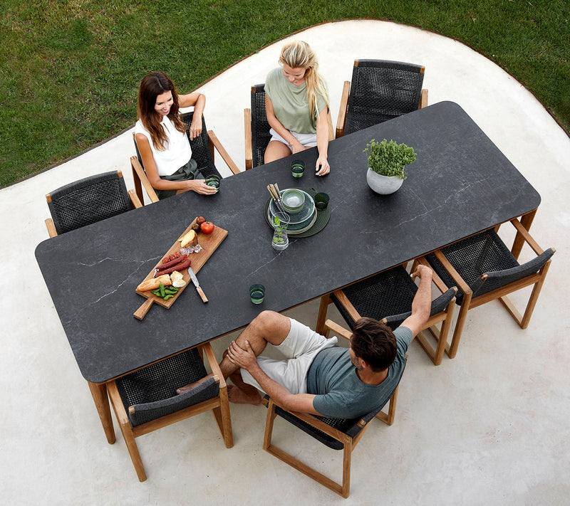 Black rectangular table with six chairs and three people sitting around it