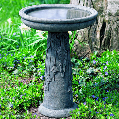 Round birdbath with flowers on the stand filled with water
