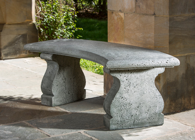 Curved bench top on decorative legs, pictured against a stone column