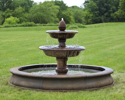 Tiered fountain with pineapple finial pictures in a green meadow.