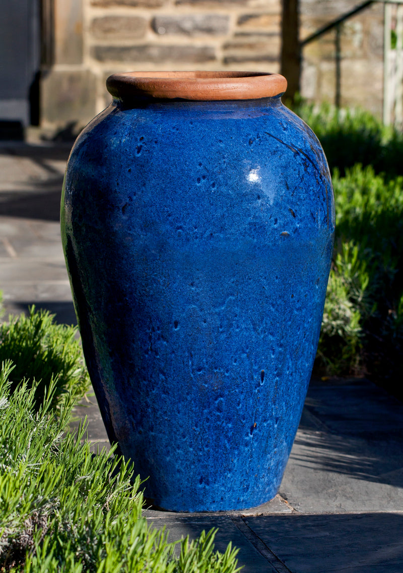 Tall blue jar in front of stone house