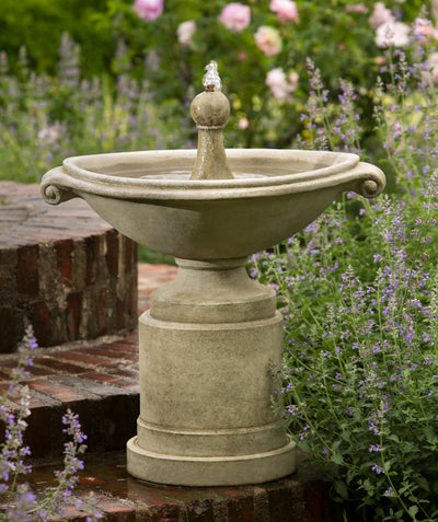 Oval fountain with round finial top with round pedestal on brick steps