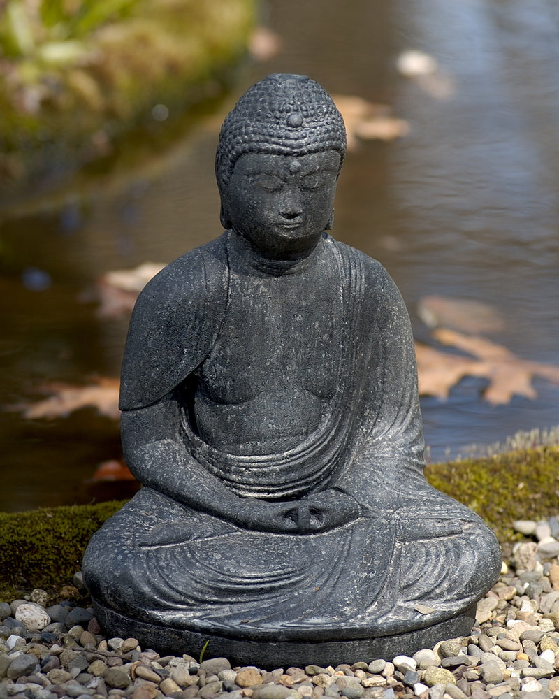 Dark gray sitting buddha by edge of water