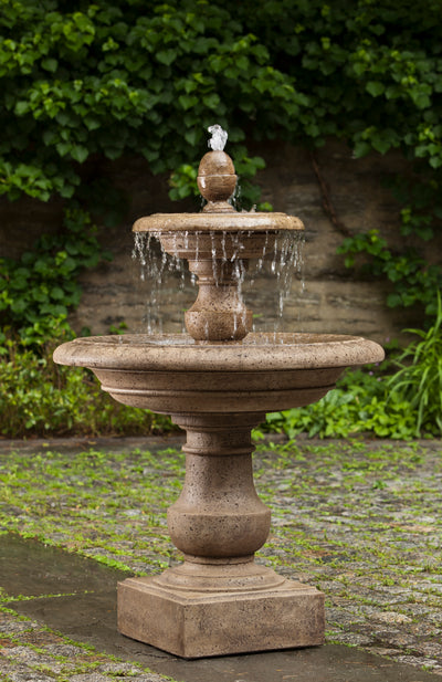 Two-tired light brown fountain with finial top standing on top of square plinth
