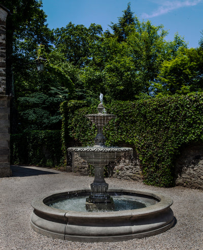 Large tow-tired fountain with water spilling in above ground round basin