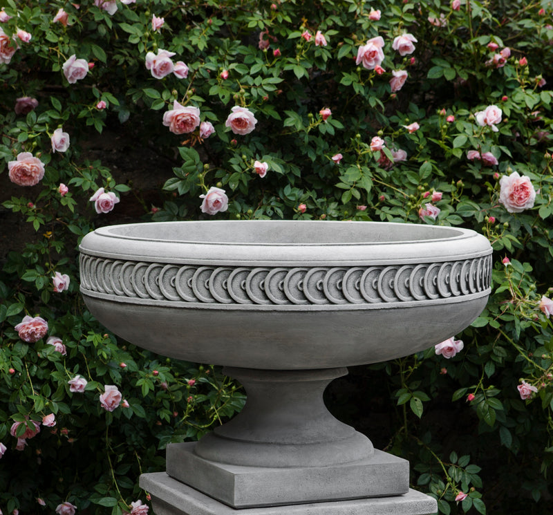 Grey urn with detailed rim shown in front of roses
