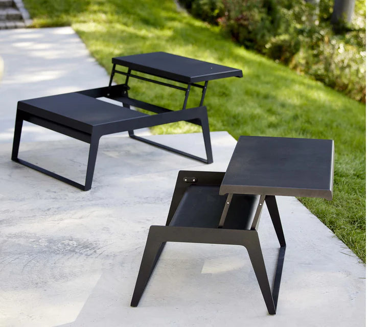 Black coffee tables on concrete patio next to lawn
