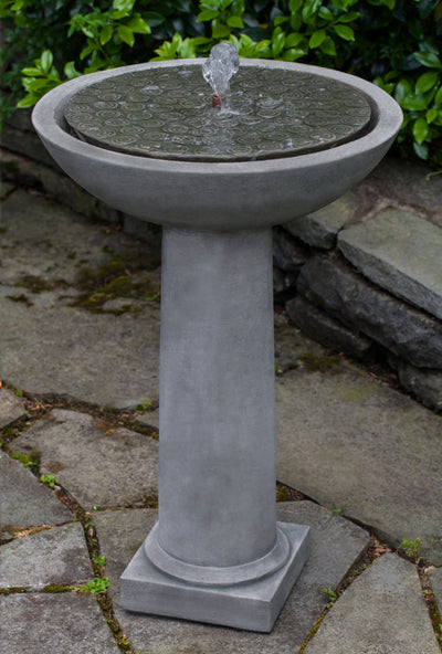 Round fountain bowl with covered top and copper spout on top of cylindrical pedestal and square plinth