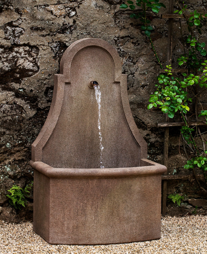 Wall fountain with rectangular basin and one large spout on curved back in front of stone wall