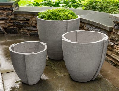 Grouping of 3 light grey containers shown in front of stone wall