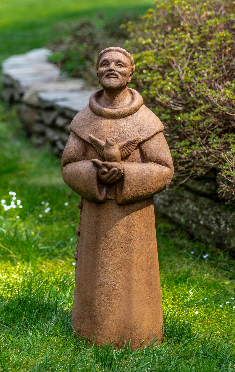 Saint Francis standing on lawn and holding a bird