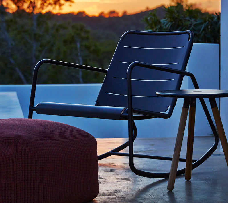 Contemporary back rocking chair behind red fabric stool at sunset