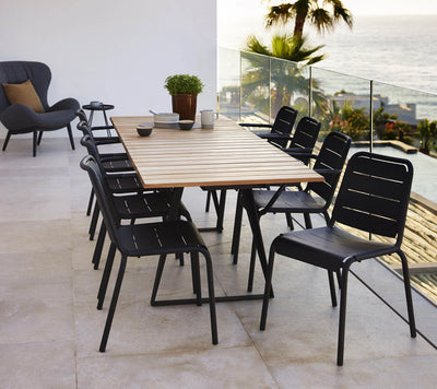 Rectangular table with black metal chairs on upper terrace by the ocean