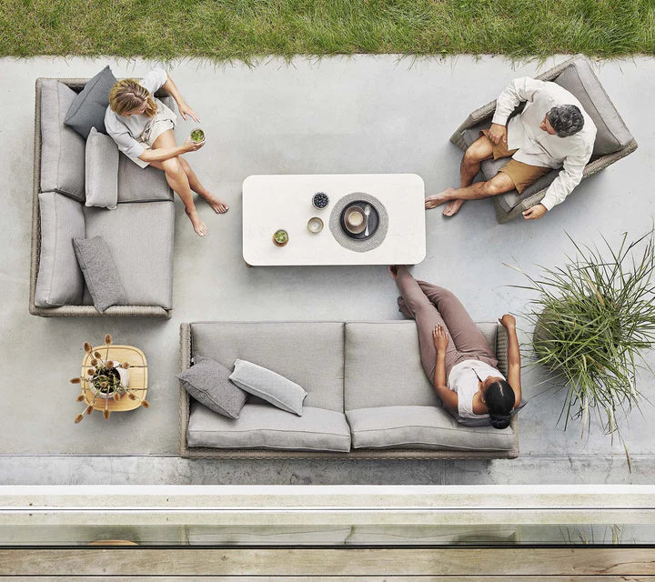 Top view of set of 2 couches and 1 armchair with three people sitting in front of coffee table
