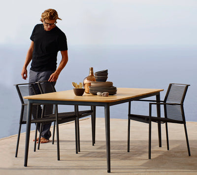 Man standing over dining table and two chairs by the ocean