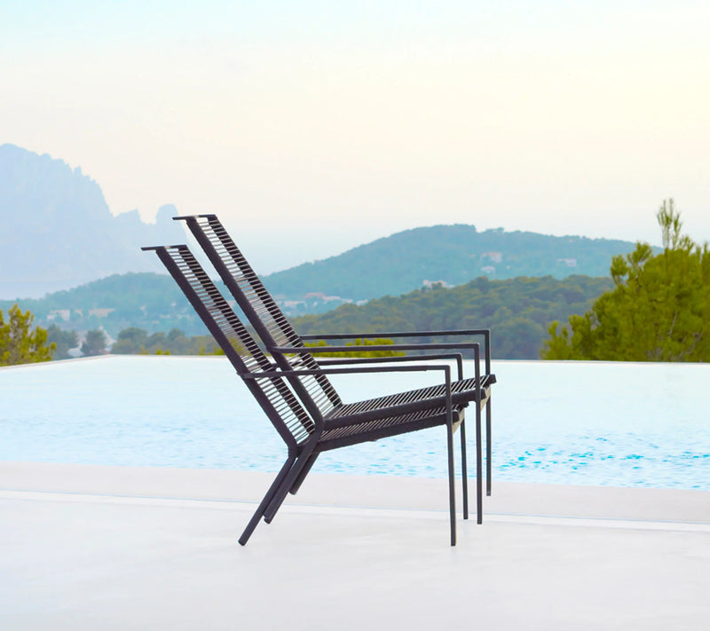 Two high back woven armchairs next to a pool