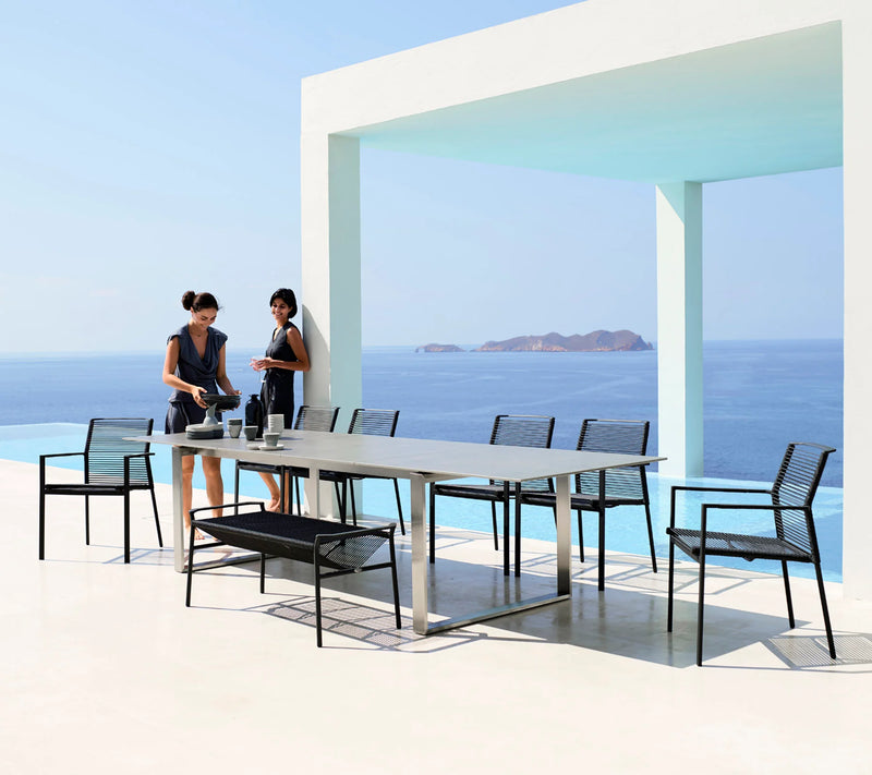 Two woman standing by rectangular dining table and chairs by the ocean