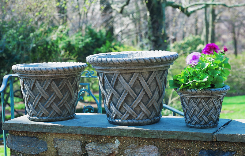 Grouping of 3 basket weave containers shown on top of a stone wall