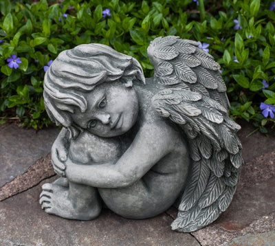 Small angel sitting with head on knees and folded wings