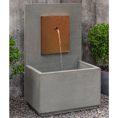 Wall fountain with spout coming out of copper plaque, framed by two potted shrubs
