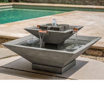 Square and angled fountain with two tiers and water spilling from four copper spouts pictured in front of a pool
