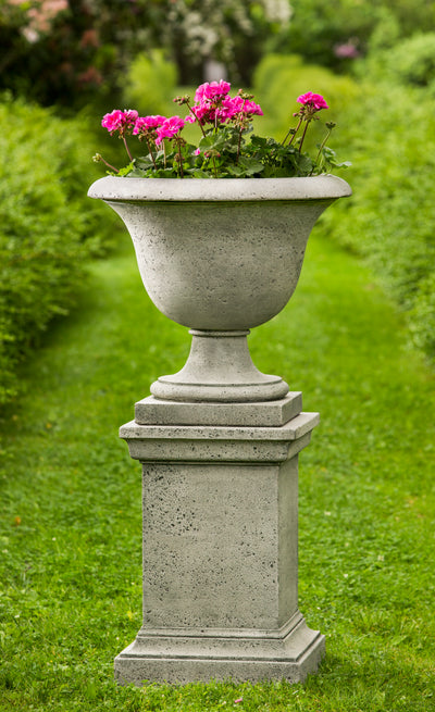 Square pedestal with rustic texture shown with an urn planted with geraniums