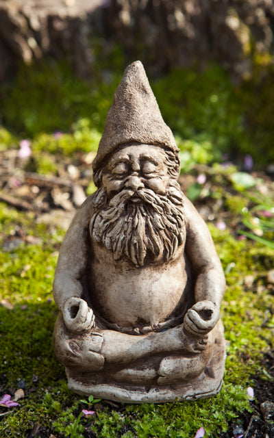 Light brown gnome sitting in yoga pose on bed of moss