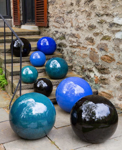 Glazed ceramic spheres in different shades of blue displayed on steps