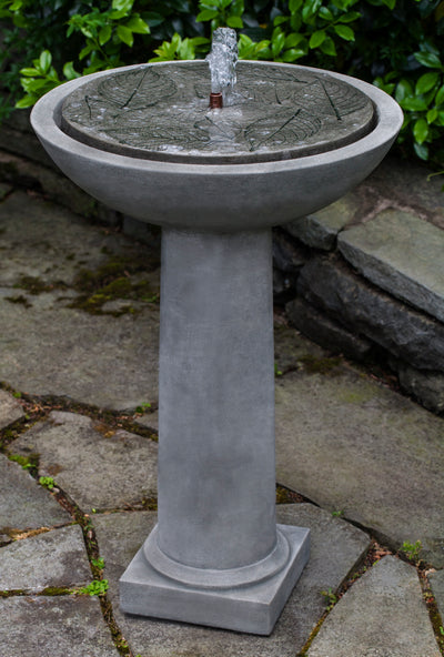 Birdbath fountain with hydrangea leaves etched on top pictured on grey stone floor