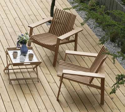 Wooden deck with two teak low armchairs in front of folding coffee table