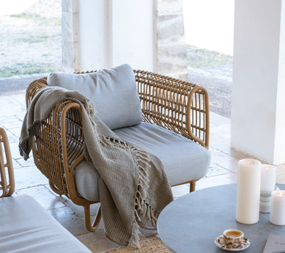 Outdoor armchair with a beige throw blanket shown on covered patio