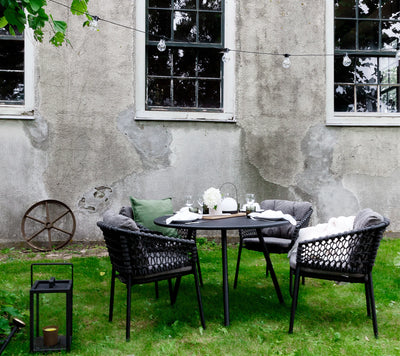 Dining set shown on grass with gray house in the background