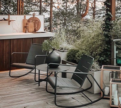 Two contemporary rocking chairs with black coffee table next to outdoor kitchen