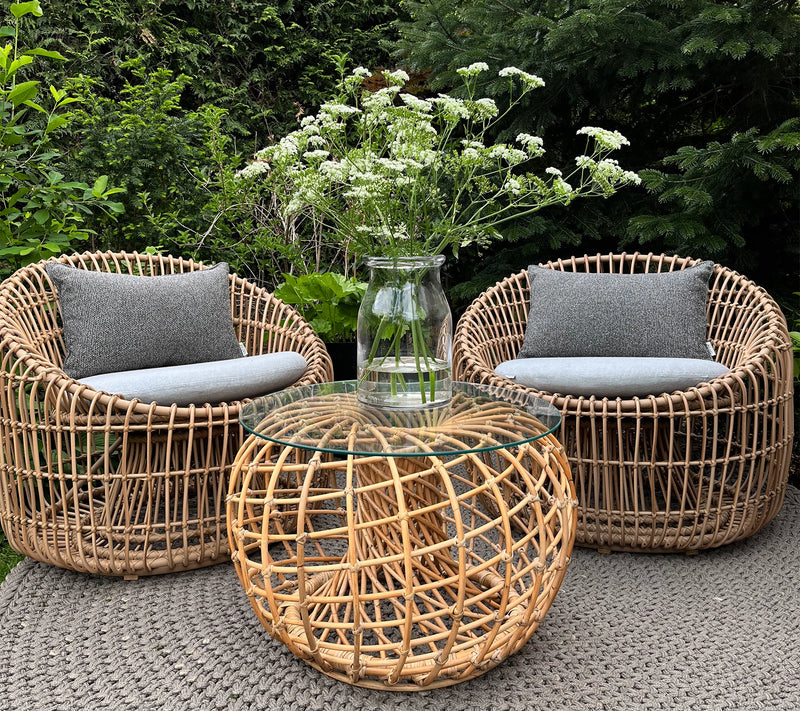 Set of two outdoor armchairs and matching coffee table with a vase and wildflowers