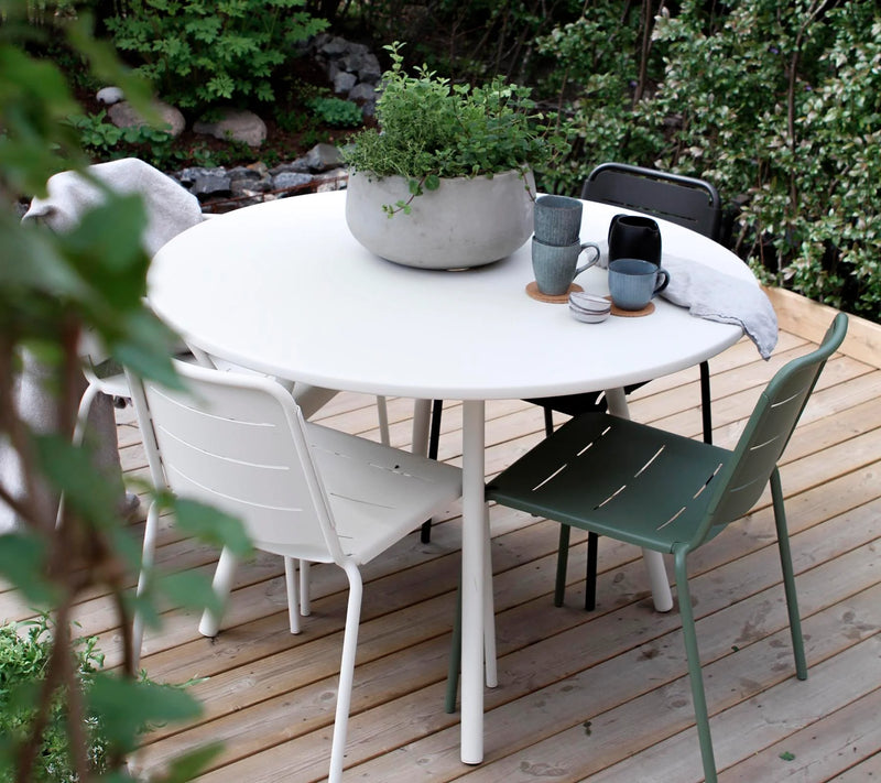 White dining set shown with green chairs and on a deck