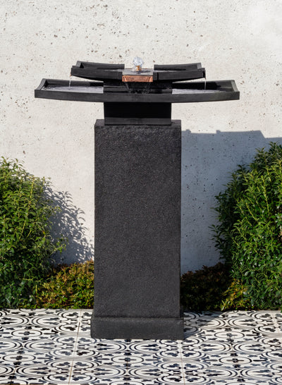 Rectangular shaped two-tiered fountain in black finish and square pedestal, pictured on black and white tiles 